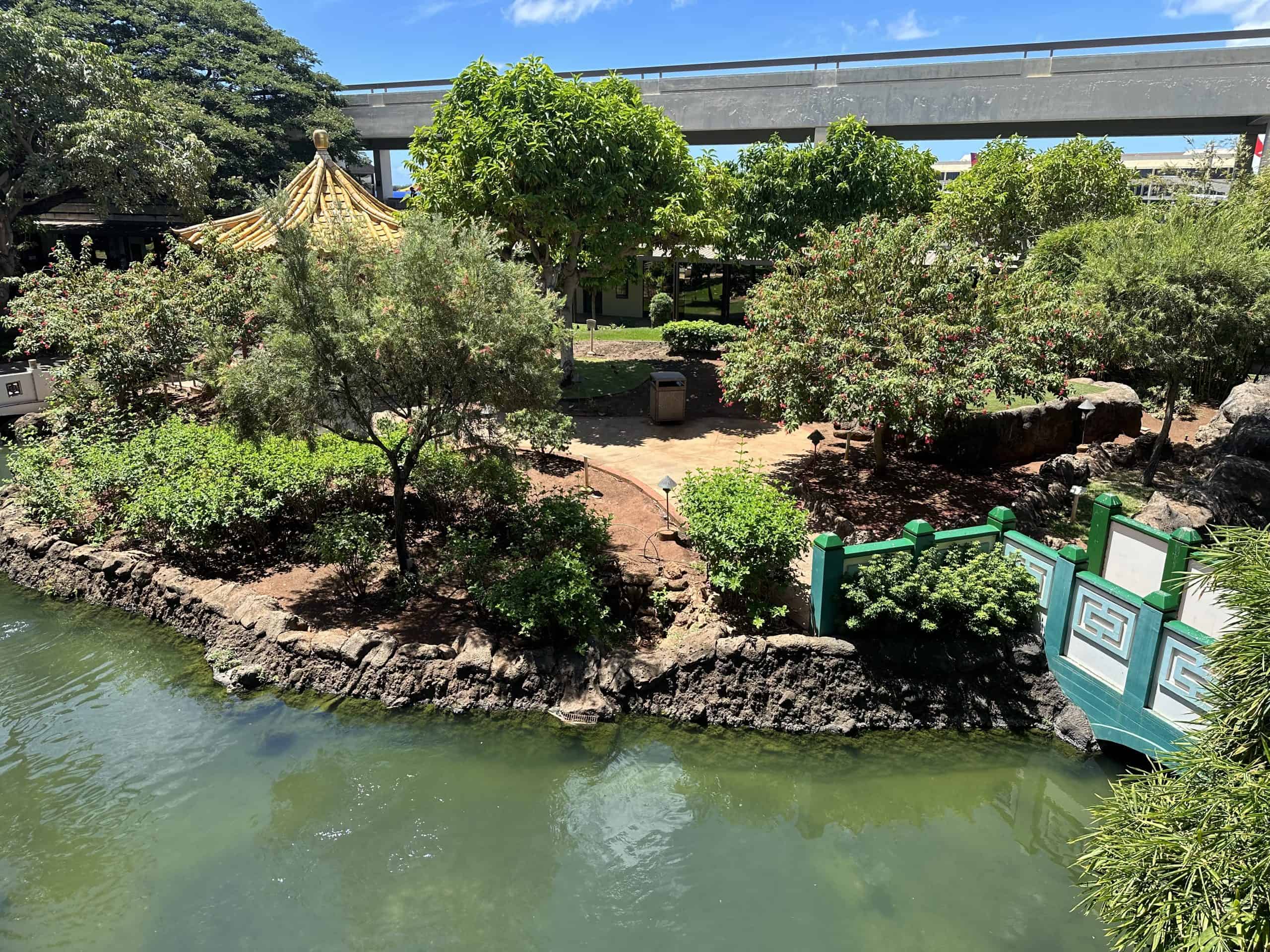 A garden at Honolulu's International Airport, with a pagoda and bridge, with water in the foreground.