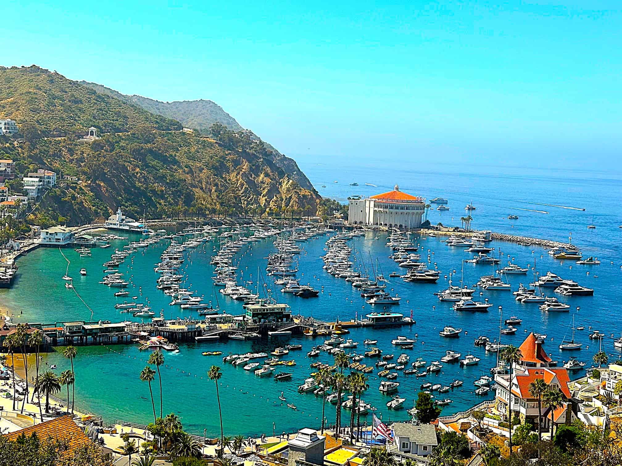 A crescent shaped bay with many boats and yachts in the water.