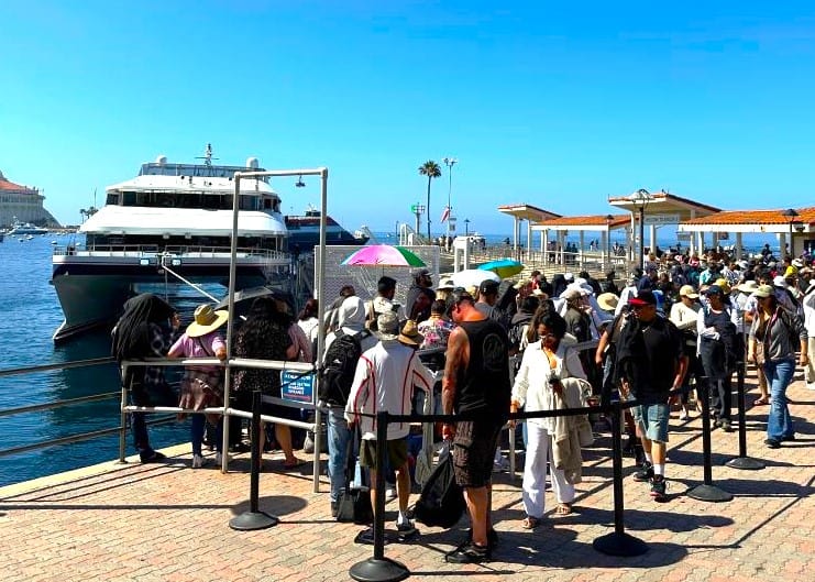  A line of many people waiting to board a large ferry to begin their day trip to Catalina Island.