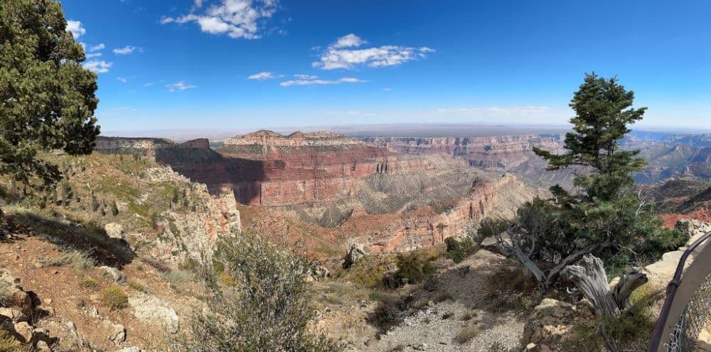 Large rocky canyon under clear blue sky with white clouds - a great place to travel in the Americas.