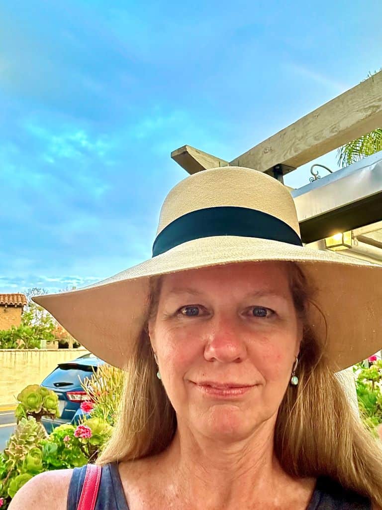 Woman wearing a wide brimmed hat, smiling toward the camera.