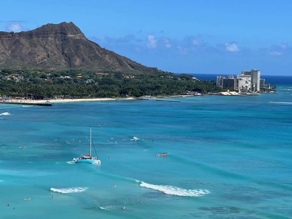 Volcano in distance with blue ocean water and beach in foreground