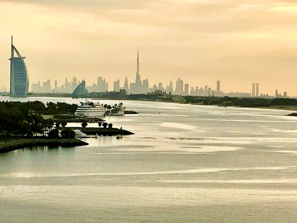 Dawn lighting over a scenic view of a skyline far in the distance behind a calm waterway.