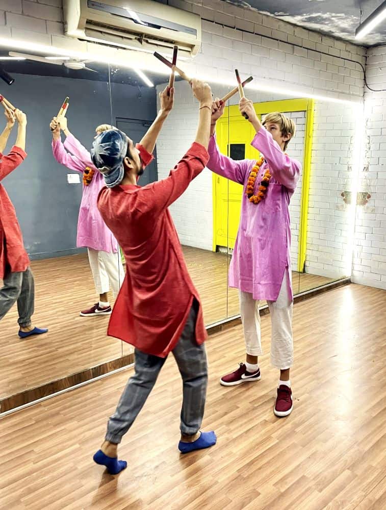 A young man takes Bollywood dancing lessons in Delhi, in a studio with white walls and mirrors.