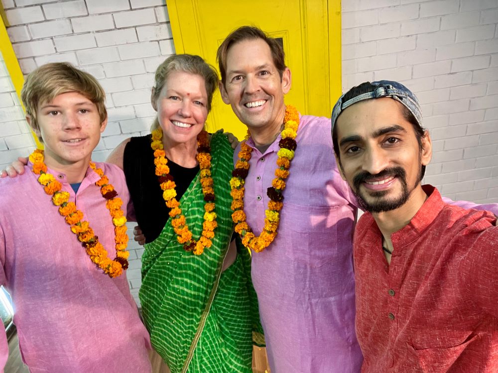 Four people, dressed in traditional clothing from India, smile into the camera.