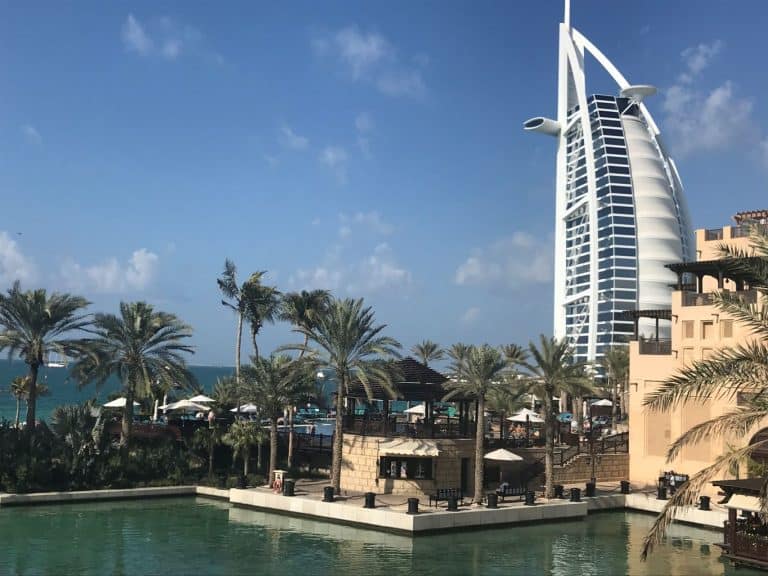 Tall white tower hotel in Dubai, standing above a water canal.