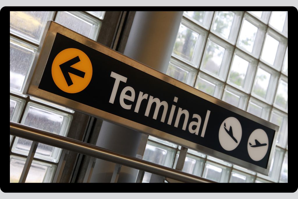 A sign in an airport with the word "Terminal" on it and an arrow pointing left.