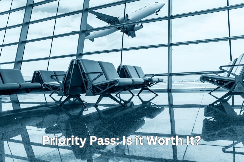 Airplane seen taking off through windows behind chairs in an airport lounge. The words, Priority Pass: Is it Worth It?" are in white.