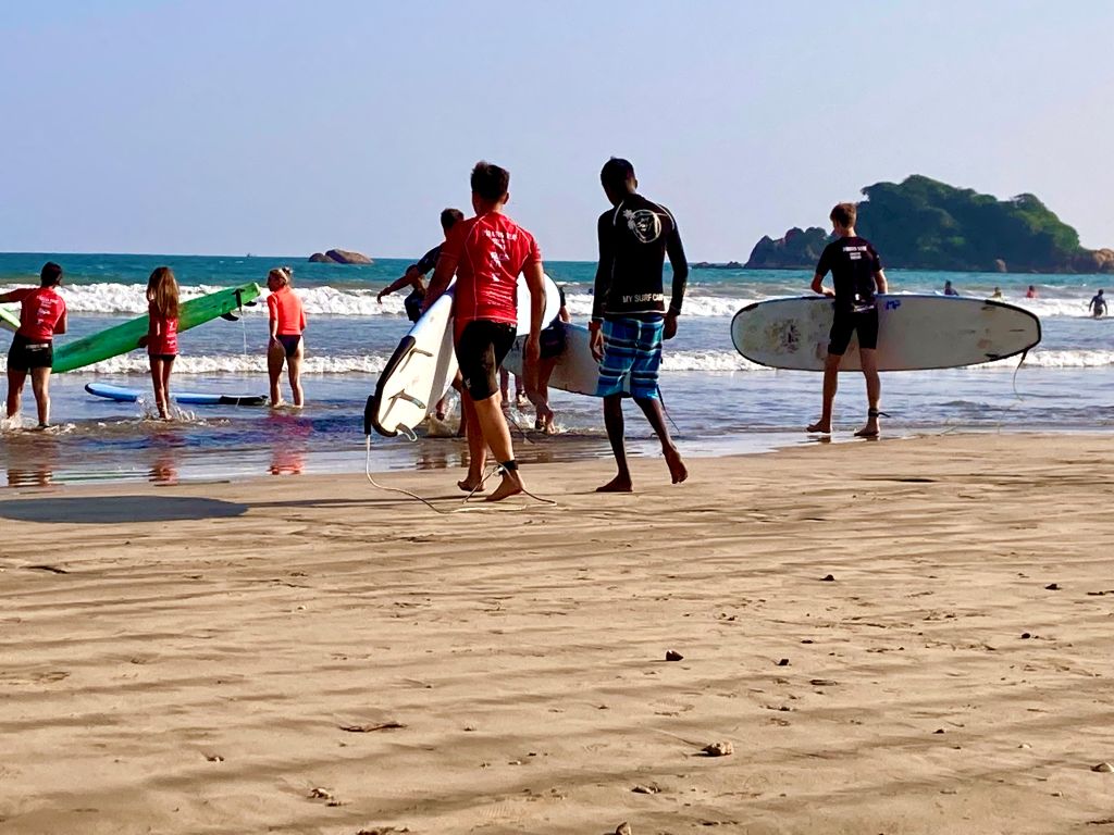 A group of children starting their surfing in Sri Lanka for Beginners lessons on a sandy beach.