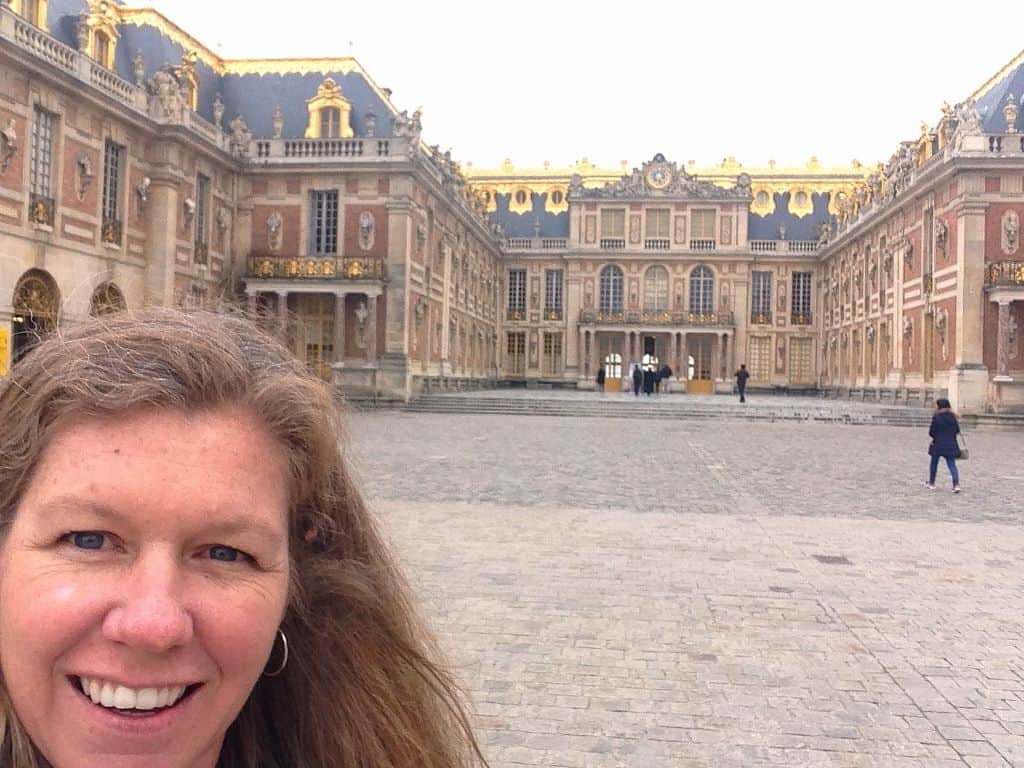 Woman standing in front of Versailles, a palace in Paris, France.