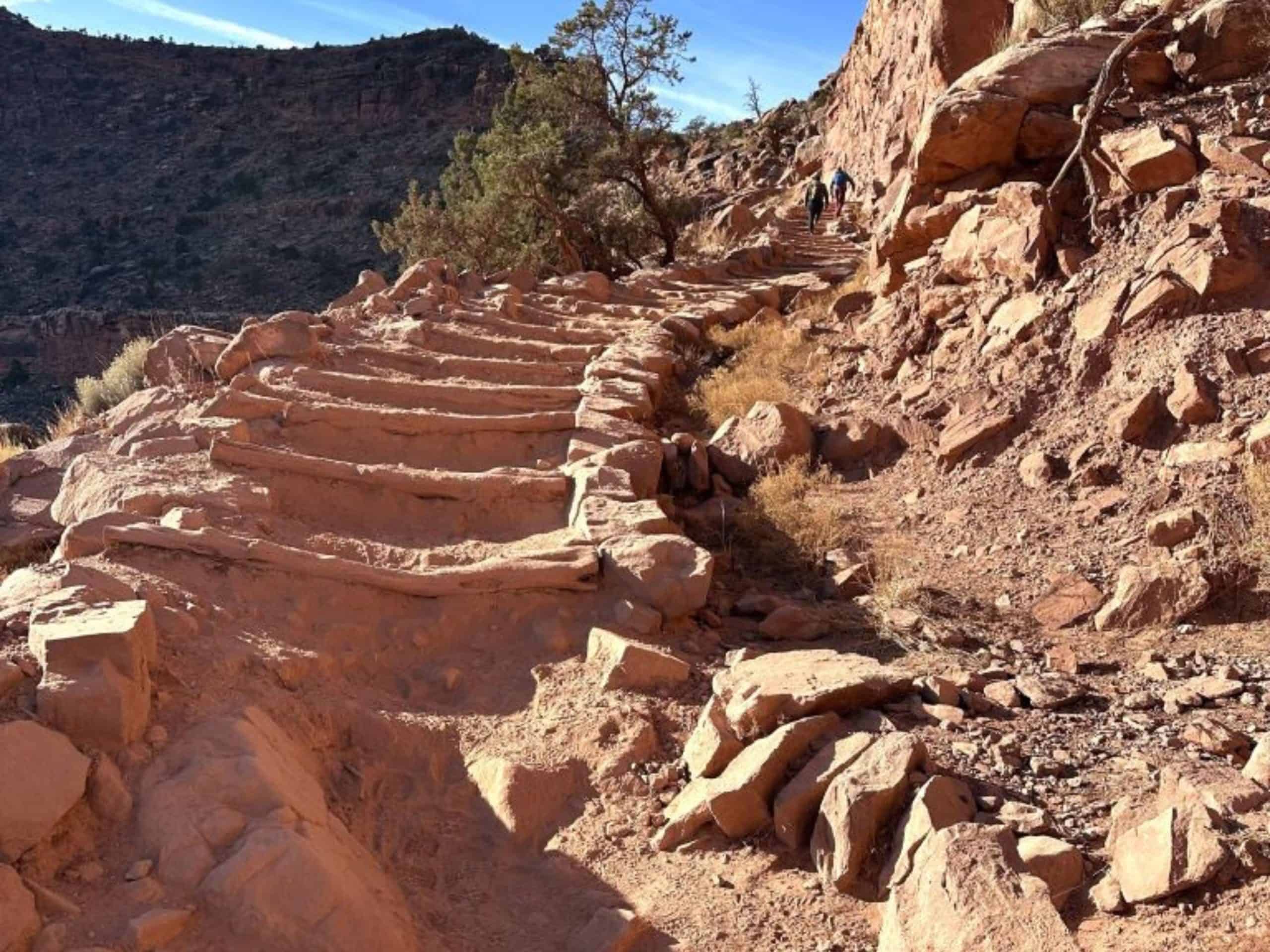 Uneven dirt and stone steps leading up a steep hill on the side of a mountain.