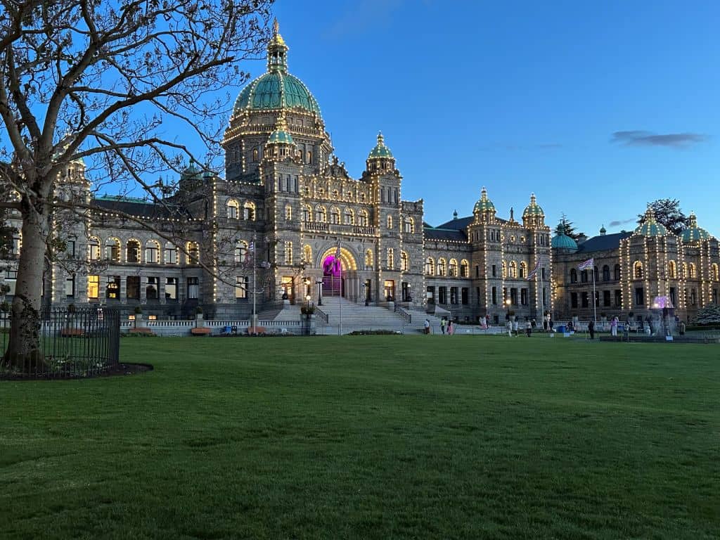The Parliament Buildings in Victoria, lit with white lights during twilight on a summer evening.