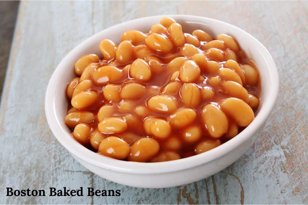 Bowl of traditional Boston baked beans with molasses and pork, shown with the text “Boston Baked Beans” overlaid on the image.