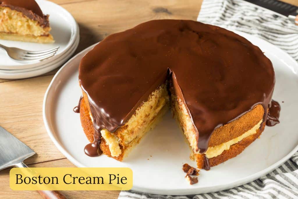 Slice of Boston cream pie with layers of sponge cake, custard filling, and chocolate glaze, shown with the text “Boston Cream Pie” overlaid on the image.