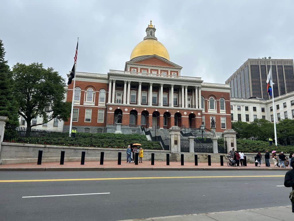 State House in Boston with a gold dome on top of a red brick building with many pillars and columns.