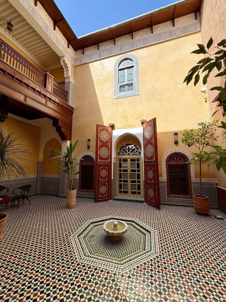 Traditional riad courtyard with mosaic tilework and carved wood details in the Meknes medina, Morocco.