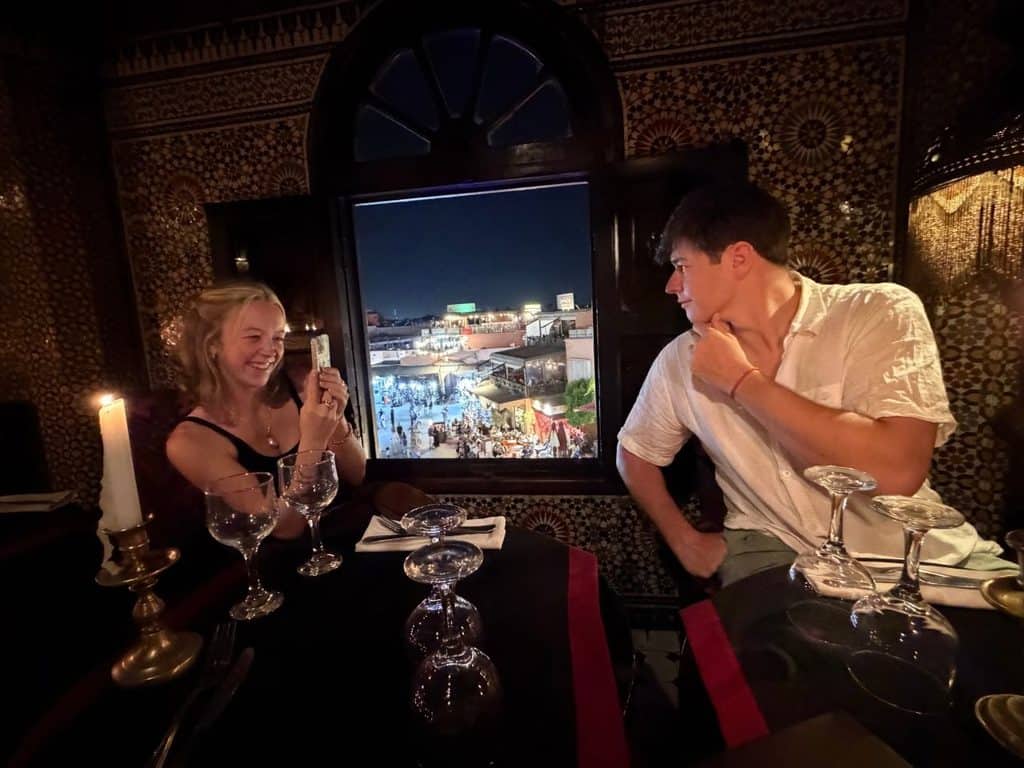 Diners overlooking Jemaa el-Fnaa at night from a restaurant in Marrakech, Morocco.