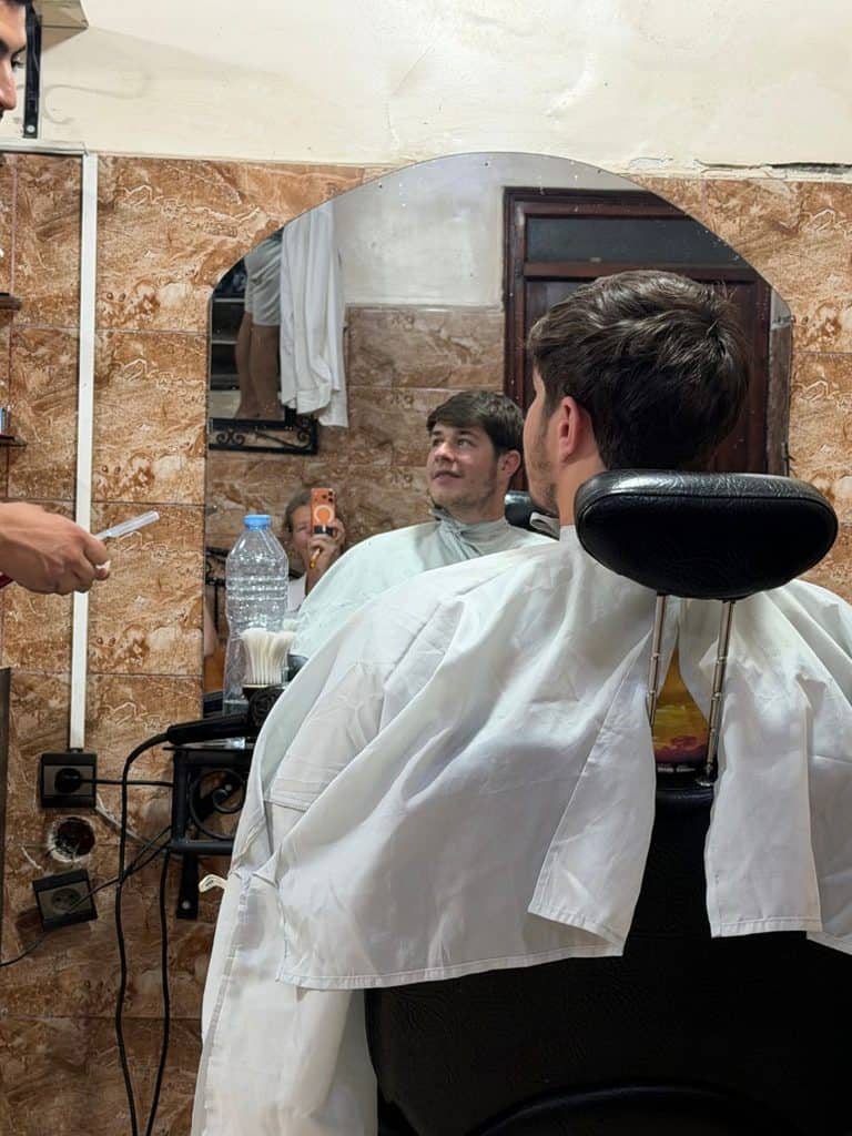 Man getting a haircut at a small barber shop in the Marrakech medina.