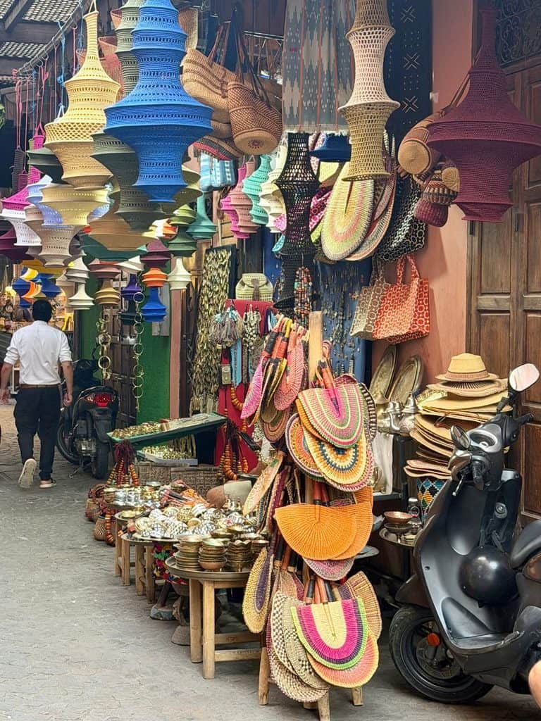 Colorful market stalls filled with hanging goods in the Marrakech medina in Morocco.