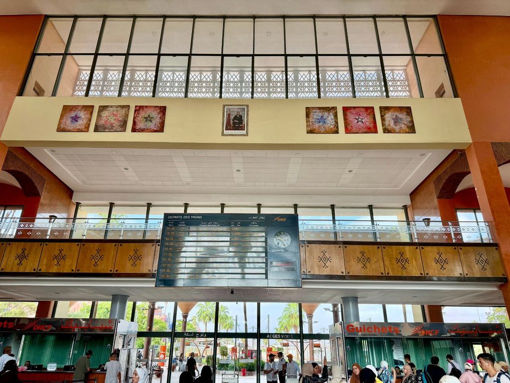Interior of Marrakech train station in Morocco with ticket counters and a train departure board.
