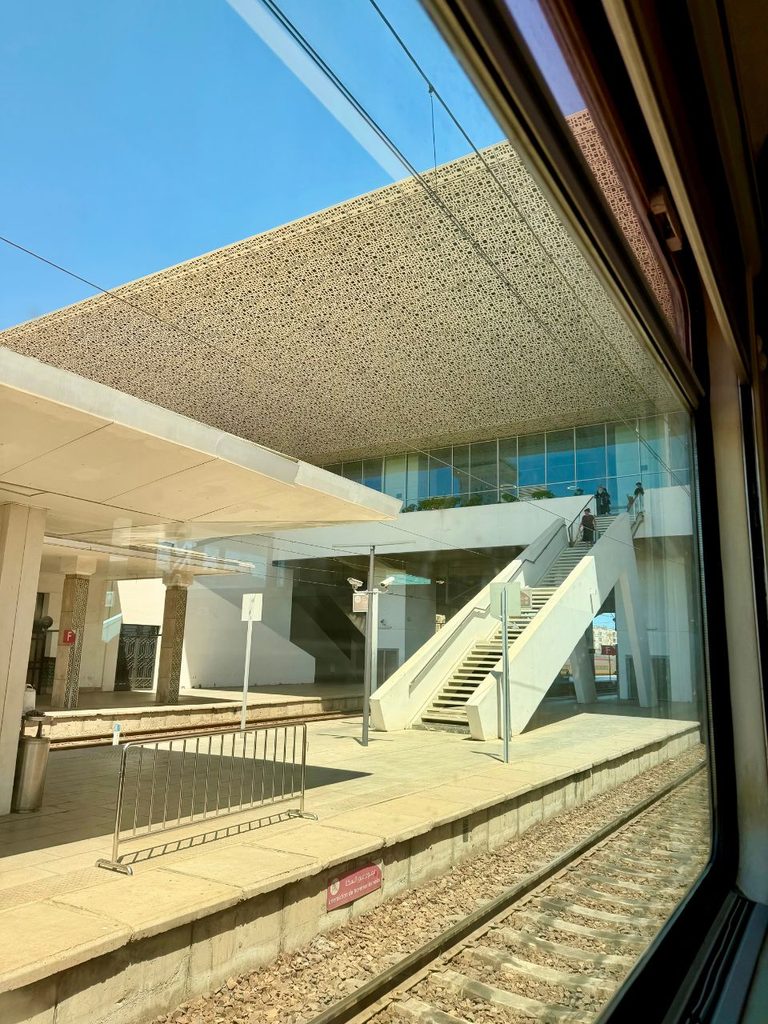 View of a train station platform through the window of a train in Morocco.